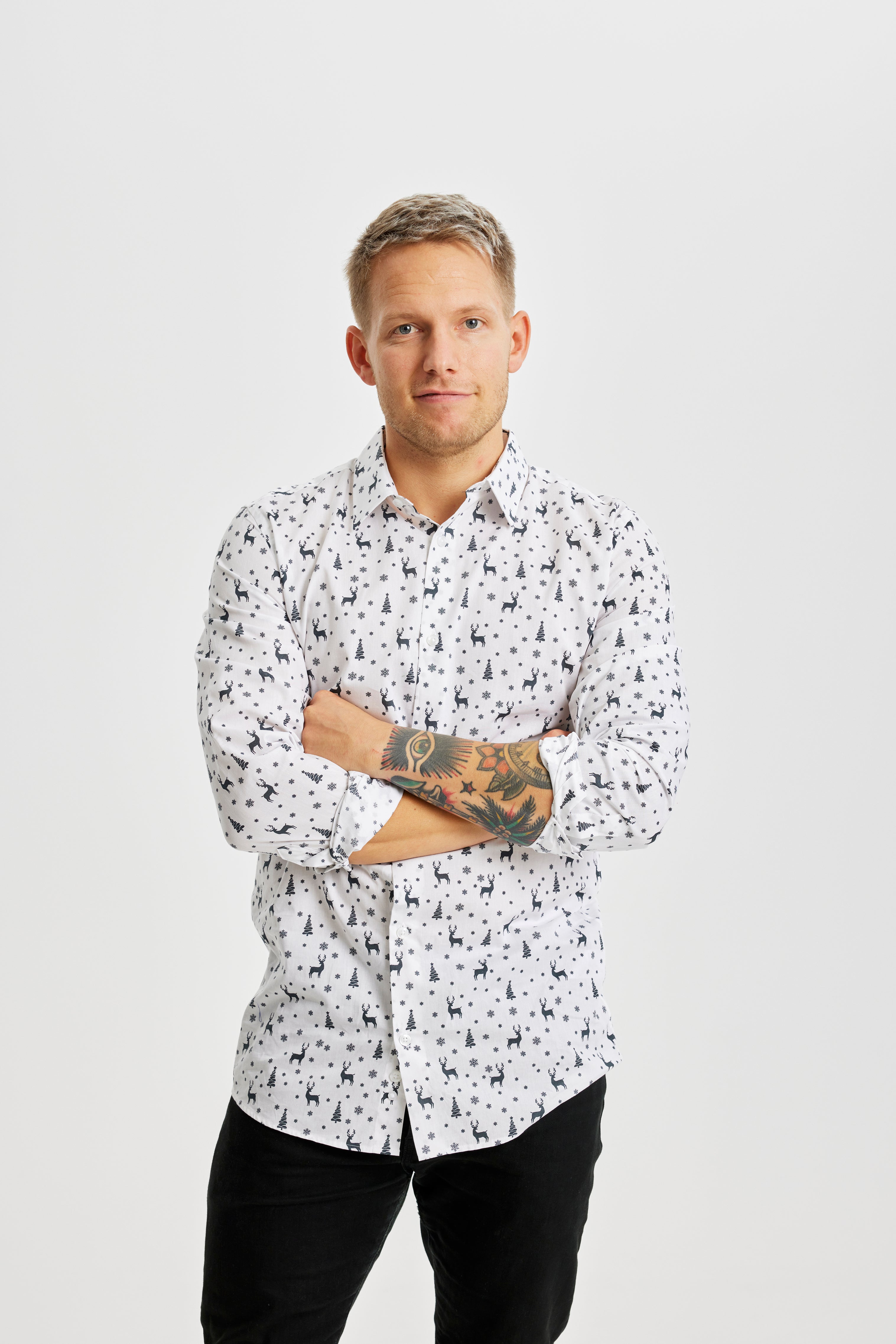 Un uomo con le braccia incrociate che indossa una camicia bianca di Natale.